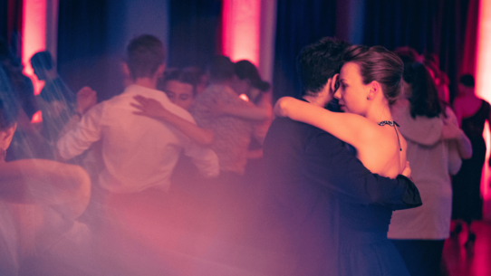 Couple dancing tango in close embrace at Milonga Baviera in Munich, social tango atmosphere.