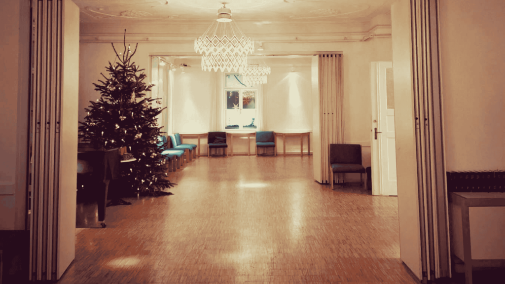 Cosy tango practica location in Munich with wooden dance floor, warm lights and seating area, used for Friday practice.