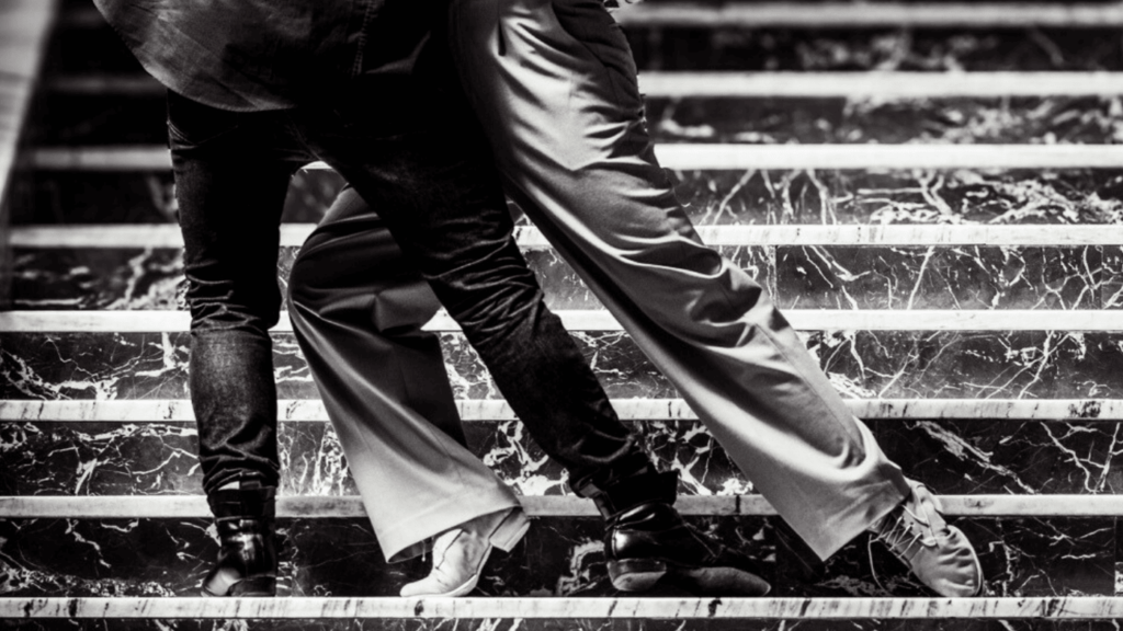 Two tango dancers balancing their weight while moving together on a staircase.