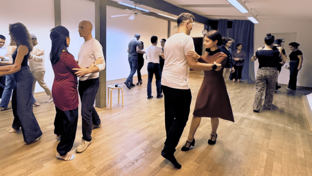 Beginner tango class at Tango Flow in Munich, students practicing Argentine tango connection and walking in a relaxed studio atmosphere.